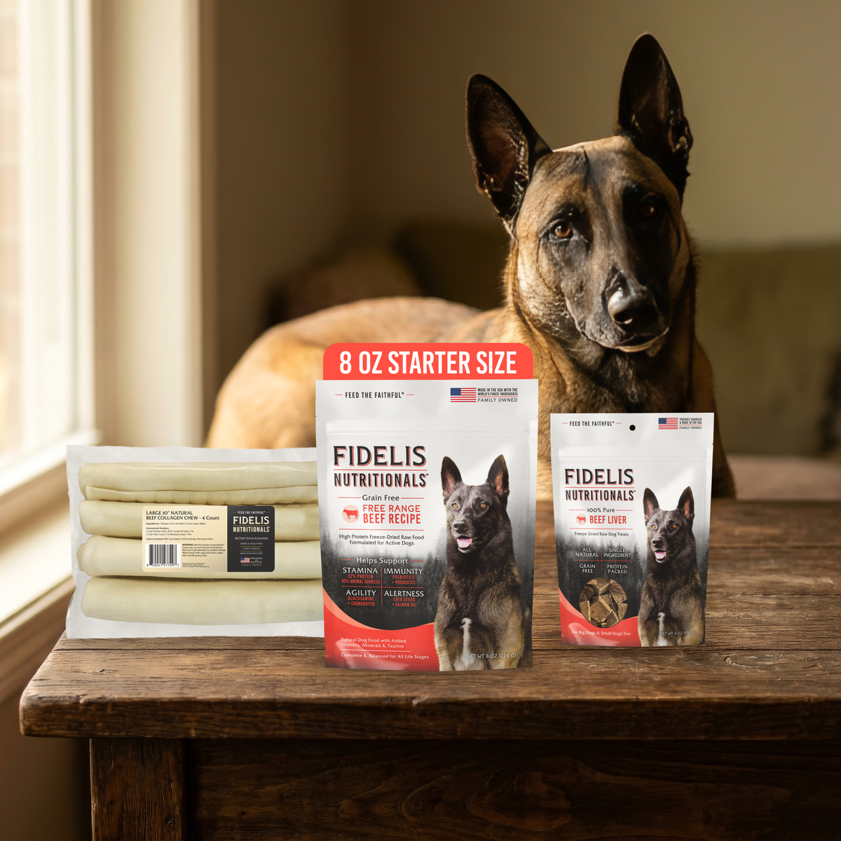 Fidelis Raw Starter Bundle on a wood table with a Belgian Malinois: 8 oz Freeze Dried Raw Beef trial bag, Large Natural Beef Collagen Chew 4 pack, and Beef Liver Treats